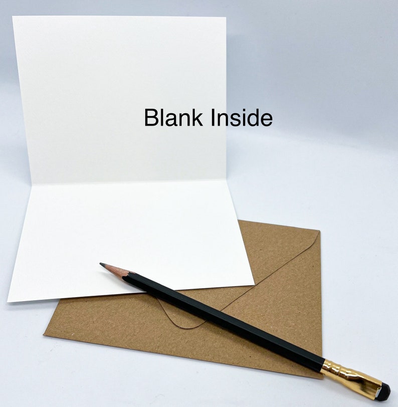 K&ouml;nnte beinhalten: Eine leere wei&szlig;e Karte mit einem braunen Umschlag und einem schwarzen Bleistift. Auf der Karte steht "Blank Inside".
