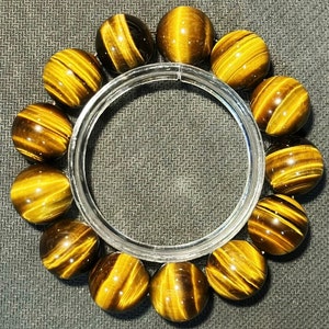 May include: A bracelet made of tiger's eye beads. The beads are a mix of brown and gold with a shimmering effect. The bracelet is strung on a clear elastic cord.