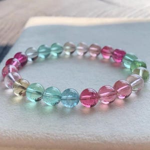 Puede incluir: Una taza de cerámica blanca con un asa negra y el texto "But First, Coffee" en negrita negra. La taza está sobre una superficie de madera. La taza mide aproximadamente 10 cm de alto.