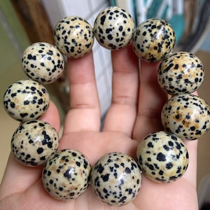 Puede incluir: Un brazalete hecho de piedras redondas, moteadas, de color marrón claro y negro.