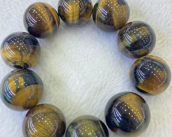 May include: A collection of polished tiger's eye gemstone spheres. The spheres display a mix of golden brown and black colors, with a glossy finish. The arrangement suggests a bracelet or decorative display.