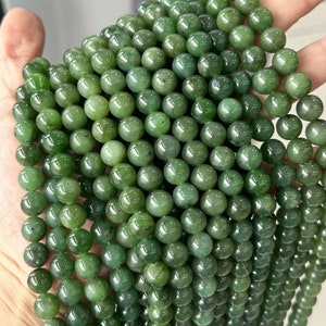 May include: A strand of round, green jade beads. The beads are smooth and polished, and they have a natural, earthy look.