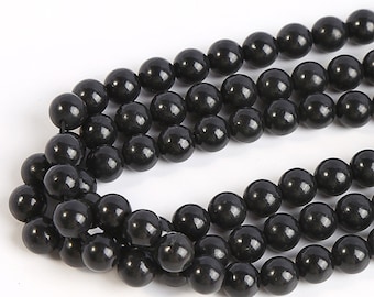 May include: A strand of black gemstone beads. The beads are round and smooth, and they are strung together on a clear thread.