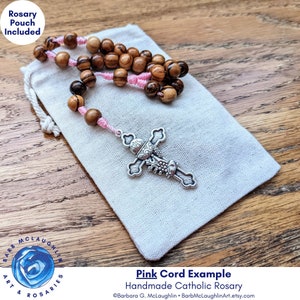 Handmade First Communion rosary with movable 7mm authentic Holy Land olive wood beads, Italian-metal cross, and pink nylon cord. This five decade rosary includes a muslin rosary pouch (approximately 3 inches by 4 inches).