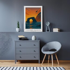 May include: A framed poster with the text "CHANNEL ISLANDS" depicts a sunset over a rock arch in the ocean. The room features a gray dresser, a gray chair, a small clock, and a plant.