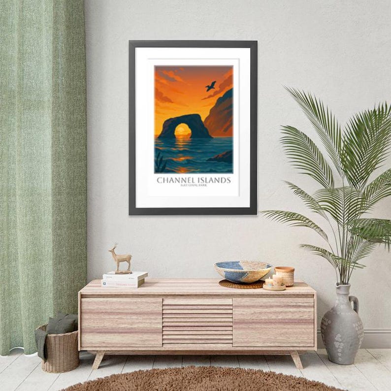 May include: Framed art print featuring a scenic view of the Channel Islands National Park. The artwork depicts a natural archway over the ocean under a vibrant orange and blue sky. The text "CHANNEL ISLANDS NATIONAL PARK" is displayed at the bottom.