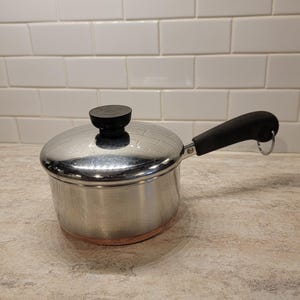 Könnte beinhalten: Ein Set aus drei Keramikbechern mit gesprenkelter, matter Oberfläche. Die Becher sind in Creme-, Hellgrau- und Dunkelgrautönen gehalten. Jeder Becher hat ein schlichtes, minimalistisches Design, perfekt für Kaffee oder Tee.