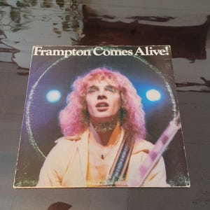 May include: A white ceramic mug with a black handle and the text "But First, Coffee" in a bold, black font. The mug is set against a blurred background, highlighting its clean design.