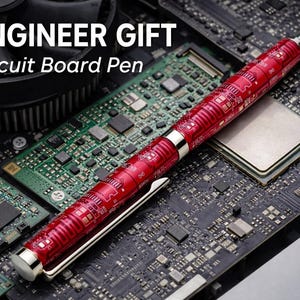 May include: A red circuit board pen with silver accents rests on a computer motherboard. The pen features a detailed circuit design. The image includes the text "ENGINEER GIFT" and "Circuit Board Pen".