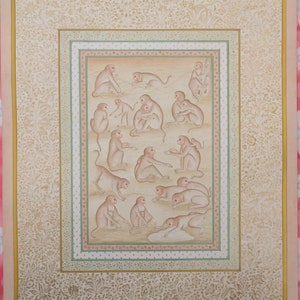 May include: A traditional Indian painting on paper depicting a group of monkeys in various poses. The painting is framed with a decorative border and has a light brown background. The monkeys are painted in shades of brown and beige, with intricate details in their fur and facial expressions. The painting is signed "AdityaRajArts" in the bottom right corner.