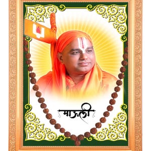 May include: A framed portrait featuring a man in orange robes and a head covering, with a white forehead marking. The portrait is surrounded by a decorative green and gold border, with a brown beaded necklace and text in the image.