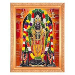 May include: A framed religious print depicting a Hindu deity with a dark complexion, adorned with garlands of flowers and standing on a pedestal. The deity is wearing a yellow and red robe and a crown. The background is a red and orange colour with a golden frame.