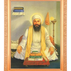 Könnte beinhalten: Ein Gemälde eines Mannes in einem weißen Turban und einer gelben Robe, der auf einem roten Kissen sitzt und vor sich einen Stapel Bücher hat. Das Gemälde ist in einem goldenen Rahmen gefasst.