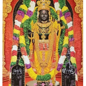 May include: A black and gold statue of a Hindu deity wearing a crown and a garland of flowers. The statue is standing on a pedestal with a floral design.