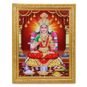 Puede incluir: Una impresión religiosa enmarcada de una diosa hindú sentada en un trono de loto. Está adornada con joyas y flores, y sostiene una cuchara y una olla. La impresión está rodeada por un marco dorado.