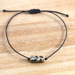 Könnte beinhalten: Ein schwarzes Armband aus Schnur mit einer rechteckigen Dalmatiner-Jaspisperle.