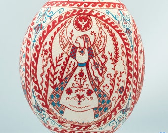 Ukrainian painting souvenir. Real pysanka on Ostrich egg. The circle of life illustration. Ivory and red handmade commemorative gift