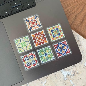 Puede incluir: Un conjunto de ocho pegatinas de azulejos coloridos con patrones geométricos. Las pegatinas están dispuestas en un patrón de cuadrícula en una computadora portátil.