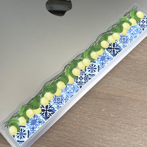 Puede incluir: Adhesivo rectangular decorativo con un diseño de limones y hojas, y un patrón de azulejos azules y blancos. El adhesivo tiene un borde transparente. Ideal para portátiles u otras superficies.