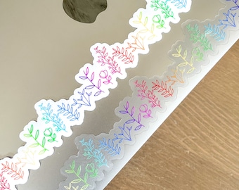May include: A set of rainbow colored floral stickers on a silver laptop. The stickers are arranged in a row, with the colors fading from red to purple.