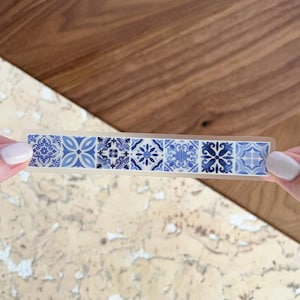 Könnte beinhalten: Eine Rolle transparentes Washi-Klebeband mit einem sich wiederholenden Muster aus blauen und weißen geometrischen Fliesen.
