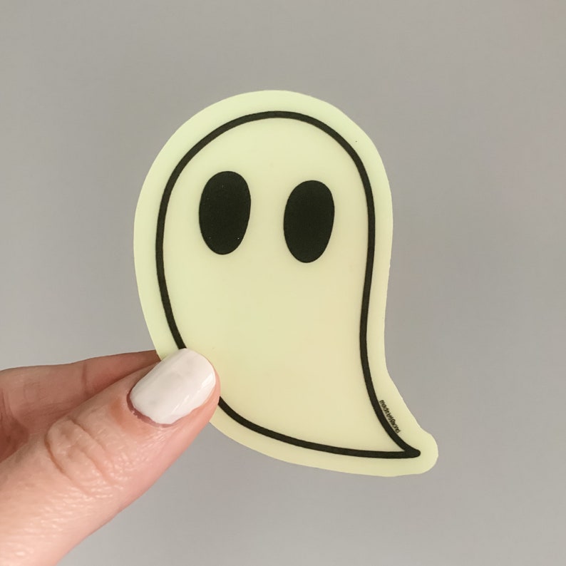 May include: A yellow glow-in-the-dark ghost sticker with black eyes. The sticker has a simple design and is perfect for adding a spooky touch to any surface.