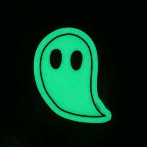 May include: A green glow-in-the-dark ghost with two black eyes. The ghost is outlined in black.