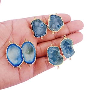May include: Five blue agate gemstone pendant connectors with gold-plated edges and jump rings. The agate is a light blue color with a white interior and a rough, natural texture.