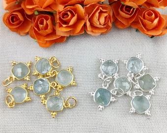 May include: Two sets of aquamarine gemstone charms with gold and silver settings. The charms are square shaped and have a loop for attaching to jewelry.