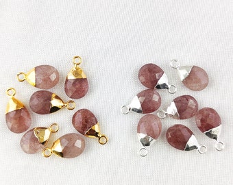 May include: A collection of 10 gemstone pendants with gold and silver accents. The pendants are teardrop shaped and have a pink and clear color.
