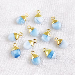 May include: Ten blue and gold teardrop-shaped gemstone pendants with a gold bail. The gemstones are a light blue colour with a white swirl pattern.