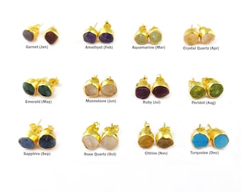 Puede incluir: Doce pares de pendientes de oro con piedras preciosas de diferentes colores, cada par representa un mes diferente del año. Las piedras preciosas son: granate, amatista, aguamarina, cuarzo rosa, esmeralda, piedra lunar, rubí, peridoto, zafiro, cuarzo rosa, citrino y turquesa.