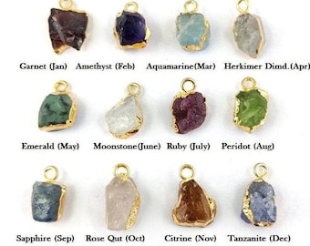 May include: Twelve gold-plated charms, each featuring a different gemstone, representing the birthstones for each month of the year. The charms are arranged in three rows of four, with the month and birthstone name listed below each charm.