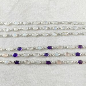 May include: Five silver bracelets with oval-shaped gemstones. The top two bracelets feature white moonstone gemstones. The bottom three bracelets feature white moonstone gemstones with alternating amethyst gemstones.