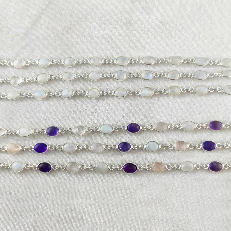 May include: Five silver bracelets with oval-shaped gemstones. The top two bracelets feature white moonstone gemstones. The bottom three bracelets feature white moonstone gemstones with alternating amethyst gemstones.
