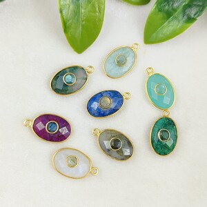 May include: Eight oval-shaped gemstone pendants with gold-toned accents. Each pendant features a different gemstone, including blue, green, pink, and white.