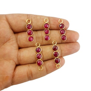 May include: Five gold-tone pendant charms with three red gemstone beads each. The charms are designed to be used as jewelry making supplies.
