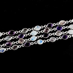 May include: A silver chain bracelet with oval-shaped gemstones in shades of purple, white, and gray.