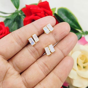 Puede incluir: Un par de pendientes de oro con piedras de luna rectangulares. Los pendientes tienen un estilo simple y minimalista.