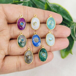 May include: Assortment of eight oval-shaped gemstone pendants with gold-toned settings. Each pendant features a different gemstone, including amethyst, blue lace agate, green aventurine, and labradorite.