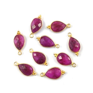 May include: Ten gold-plated teardrop-shaped ruby gemstone pendants with a loop for attaching to jewelry.
