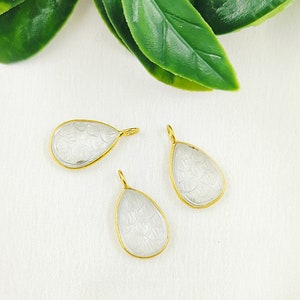 Puede incluir: Tres colgantes de cristal transparente en forma de lágrima con detalles en metal dorado. Cada colgante presenta un diseño tallado.