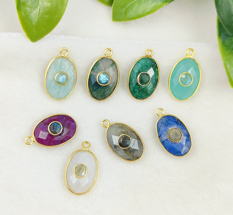 May include: Nine gold oval-shaped pendants with different colored gemstones and a small blue gemstone in the center of each pendant.