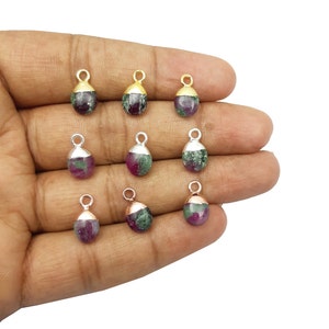 May include: Nine gemstone pendants with gold and silver accents. The pendants are teardrop shaped and feature a mix of green and pink colors.