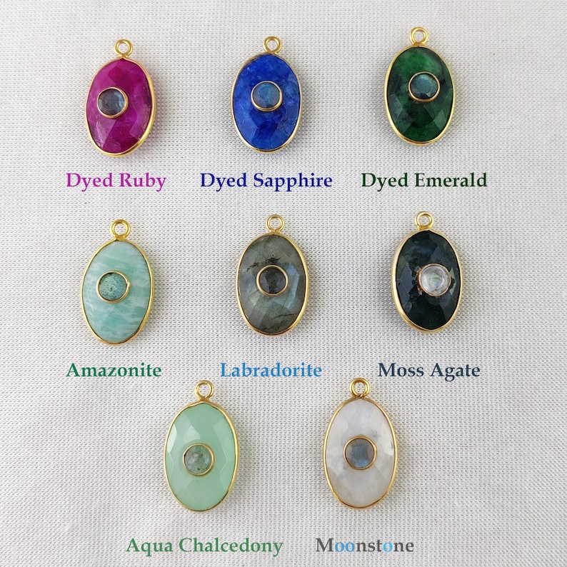 May include: Assortment of oval-shaped gemstone pendants with gold settings. The stones are dyed ruby, sapphire, emerald, amazonite, labradorite, moss agate, aqua chalcedony, and moonstone.