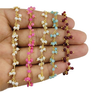 May include: Five strands of beaded jewellery in white, pink, white, light blue, and burgundy. Each strand features small, round beads strung on gold-coloured wire. The beads are clustered together, creating a delicate and intricate design.