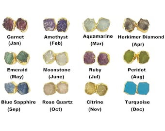 Puede incluir: Doce pares de pendientes chapados en oro con piedras preciosas de diferentes colores, cada uno representando un mes diferente del año. Las piedras preciosas son: granate, amatista, aguamarina, diamante Herkimer, esmeralda, piedra lunar, rubí, peridoto, zafiro azul, cuarzo rosa, citrino y turquesa.