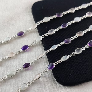 May include: Four silver chain bracelets with oval-shaped gemstones. The bracelets feature alternating moonstone, rose quartz, and amethyst gemstones.