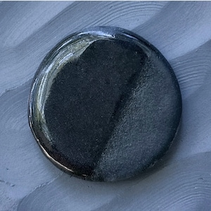 May include: A black and gray round ceramic coaster with a glossy finish.