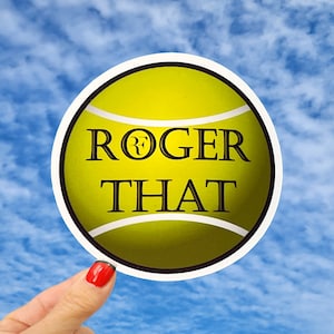 May include: A yellow tennis ball sticker with a black outline and the text "ROGER THAT" with a stylized "R" in a circle.